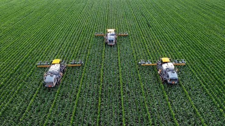 Three autonomous sprayers working perfectly spaced rows of corn