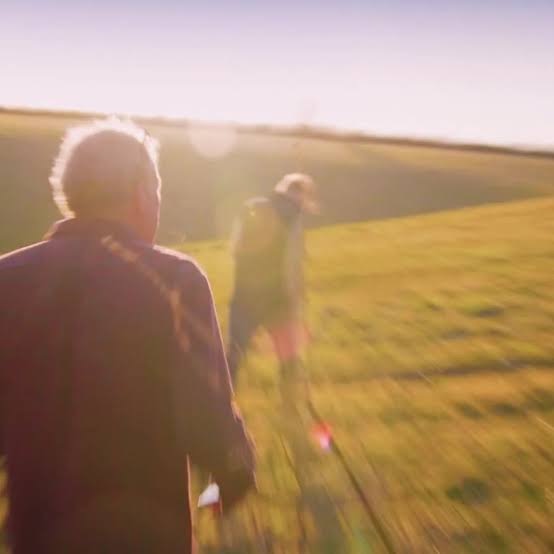 Jeremy Clarkson walking into a sunlit field at golden hour